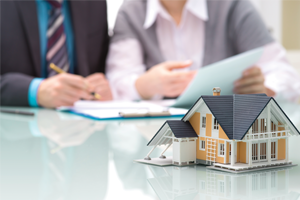 People reviewing documents with a model house on the table